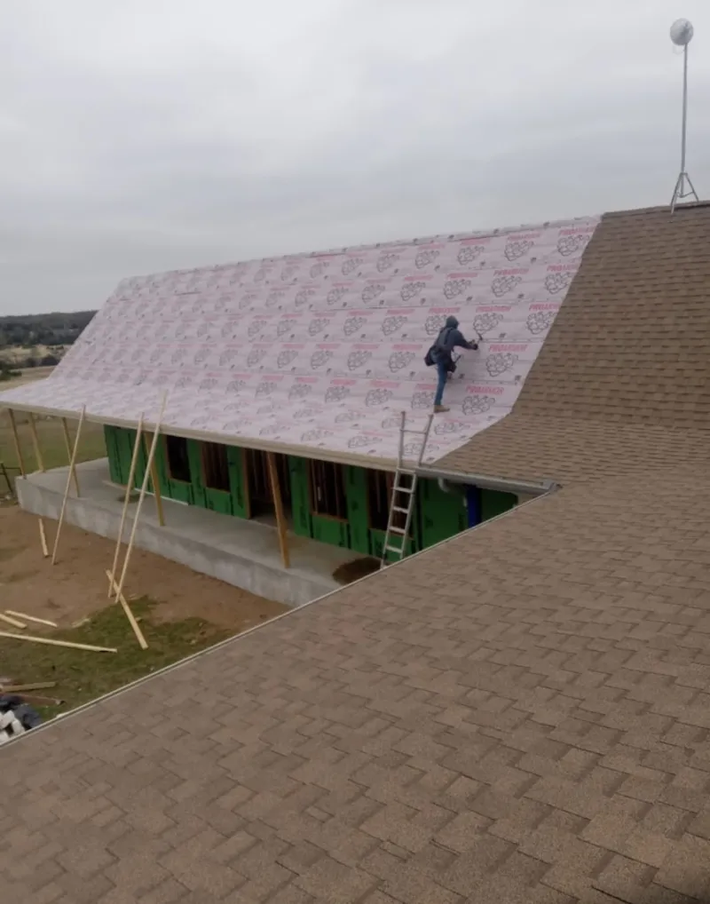 Worker preparing underlayment for a metal roof installation in Hutchinson